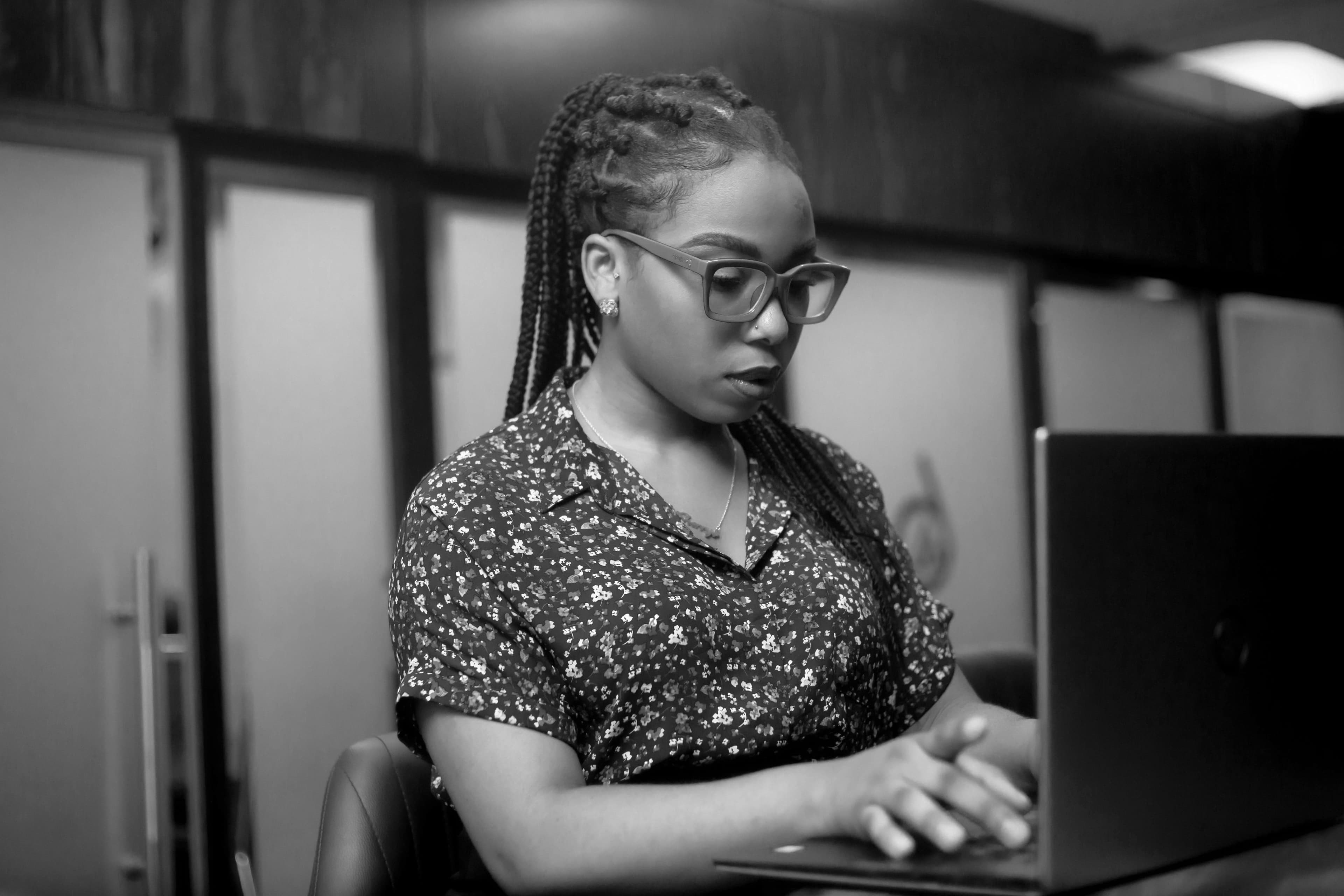 Focused black woman working on a laptop in an office setting.