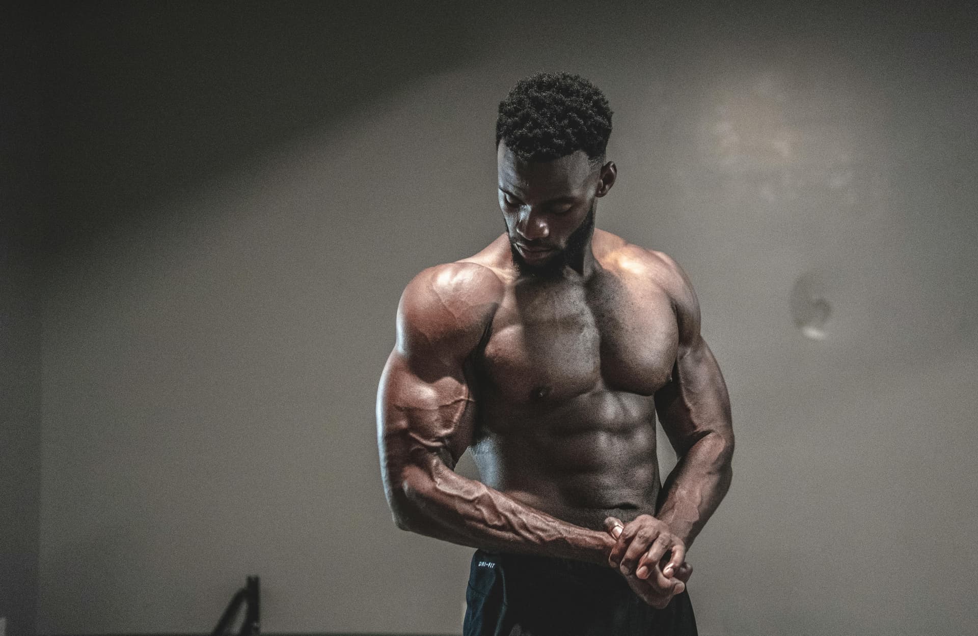 A strong, shirtless male bodybuilder showcasing muscles and strength in a gym setting.