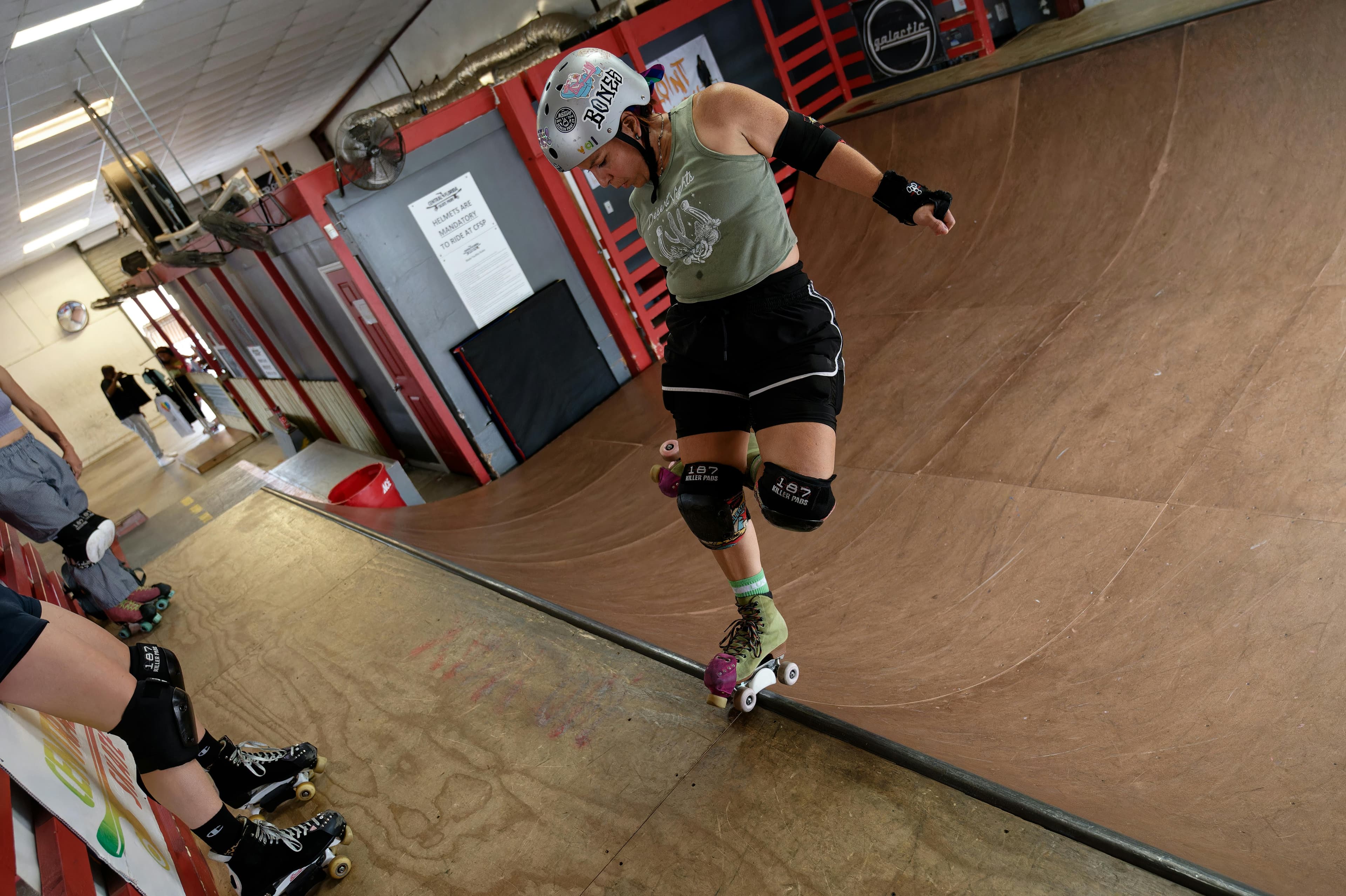 A woman performs a roller skating stunt on an indoor ramp, showcasing agility and skill.