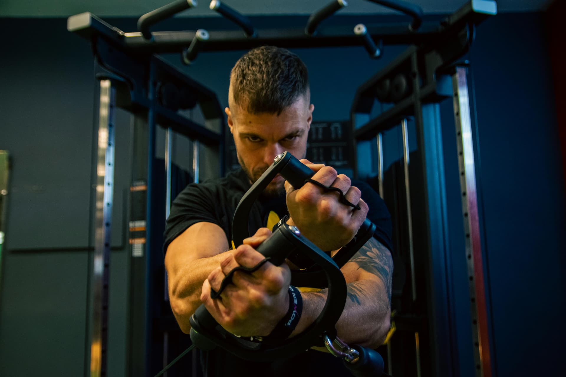 Muscular man exercising with intense focus on gym equipment.