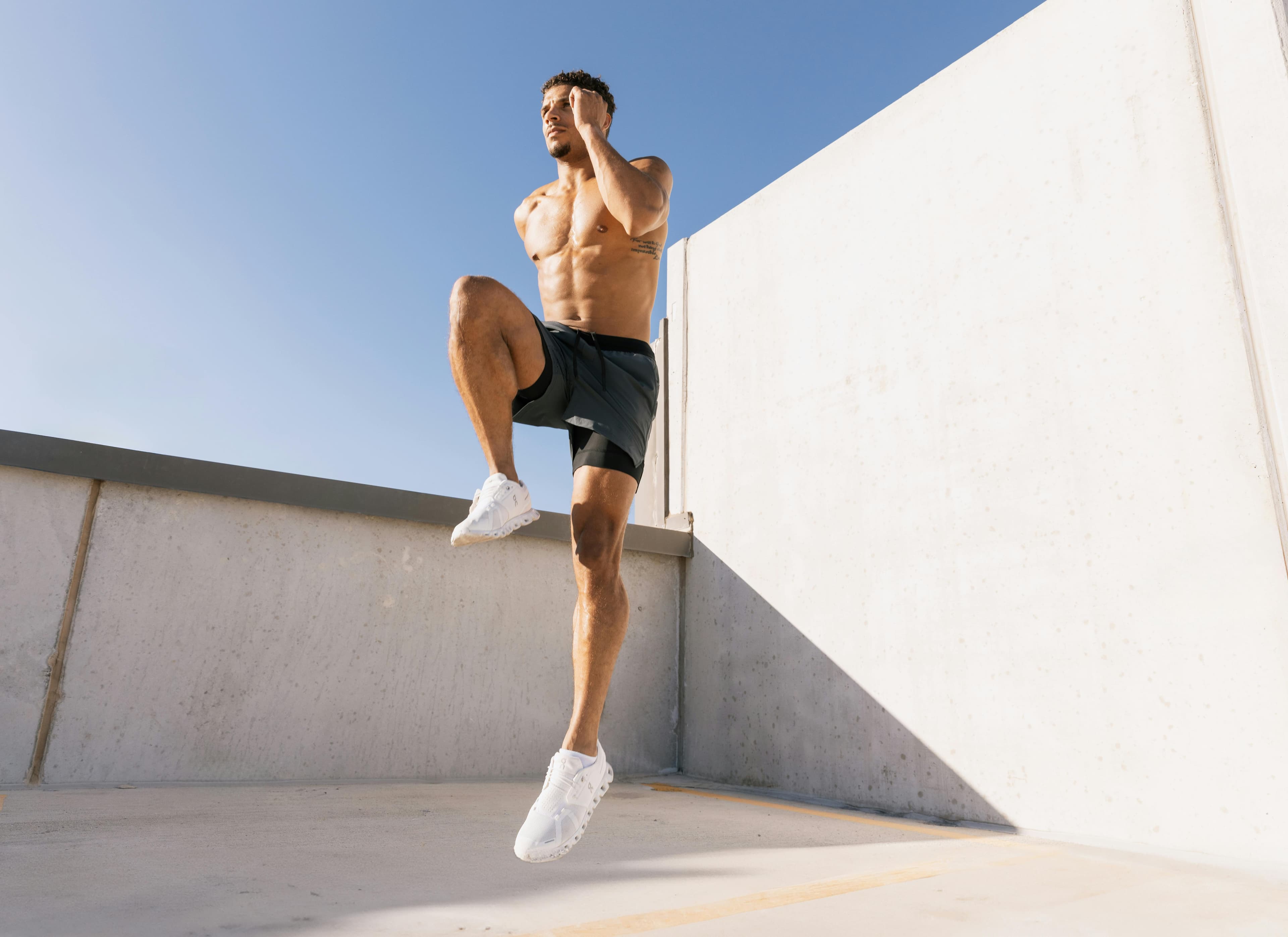 Atleta maschio che fa allenamento cardio su un tetto sotto il cielo azzurro ad Austin, Texas.