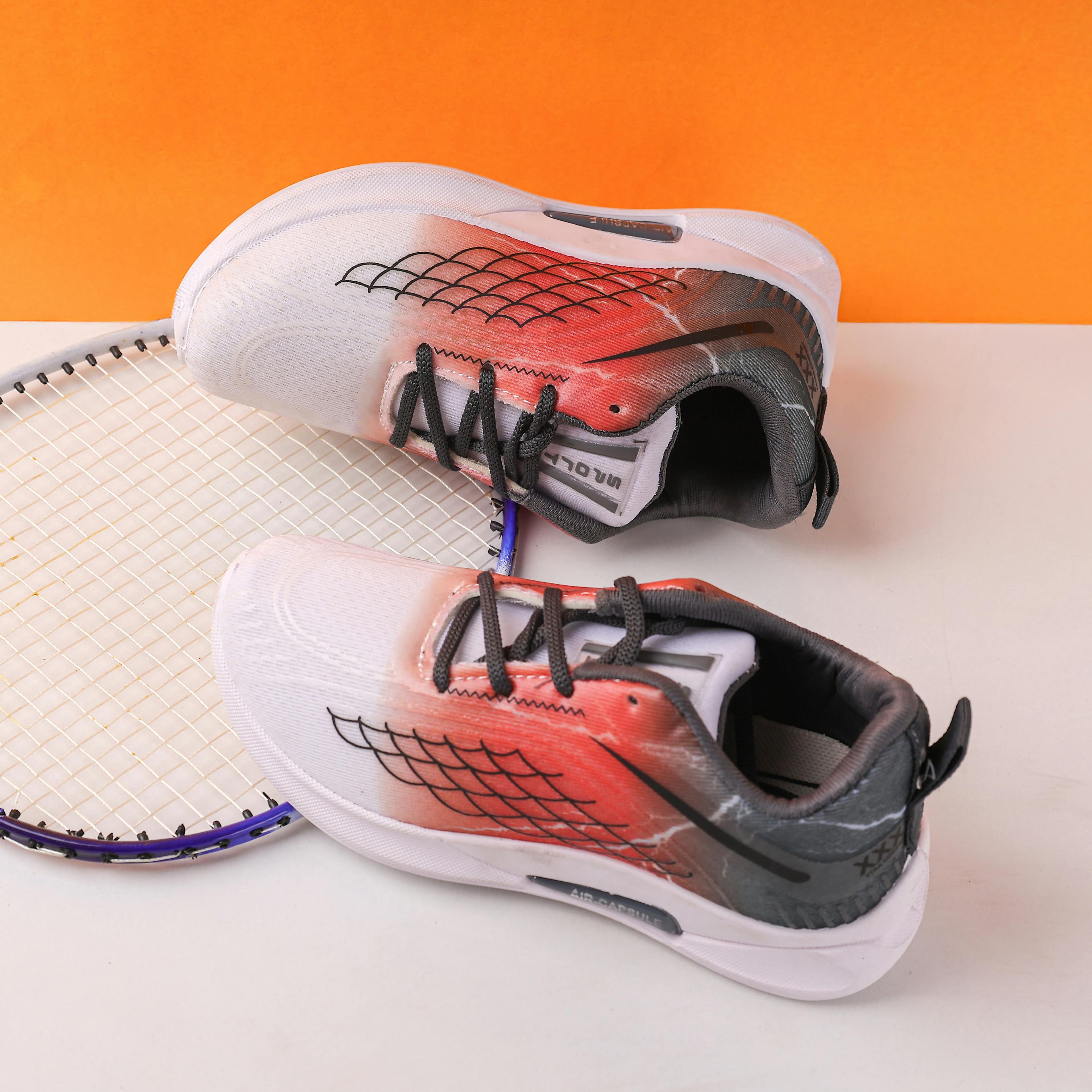 Modern athletic shoes displayed with a tennis racket against an orange backdrop.