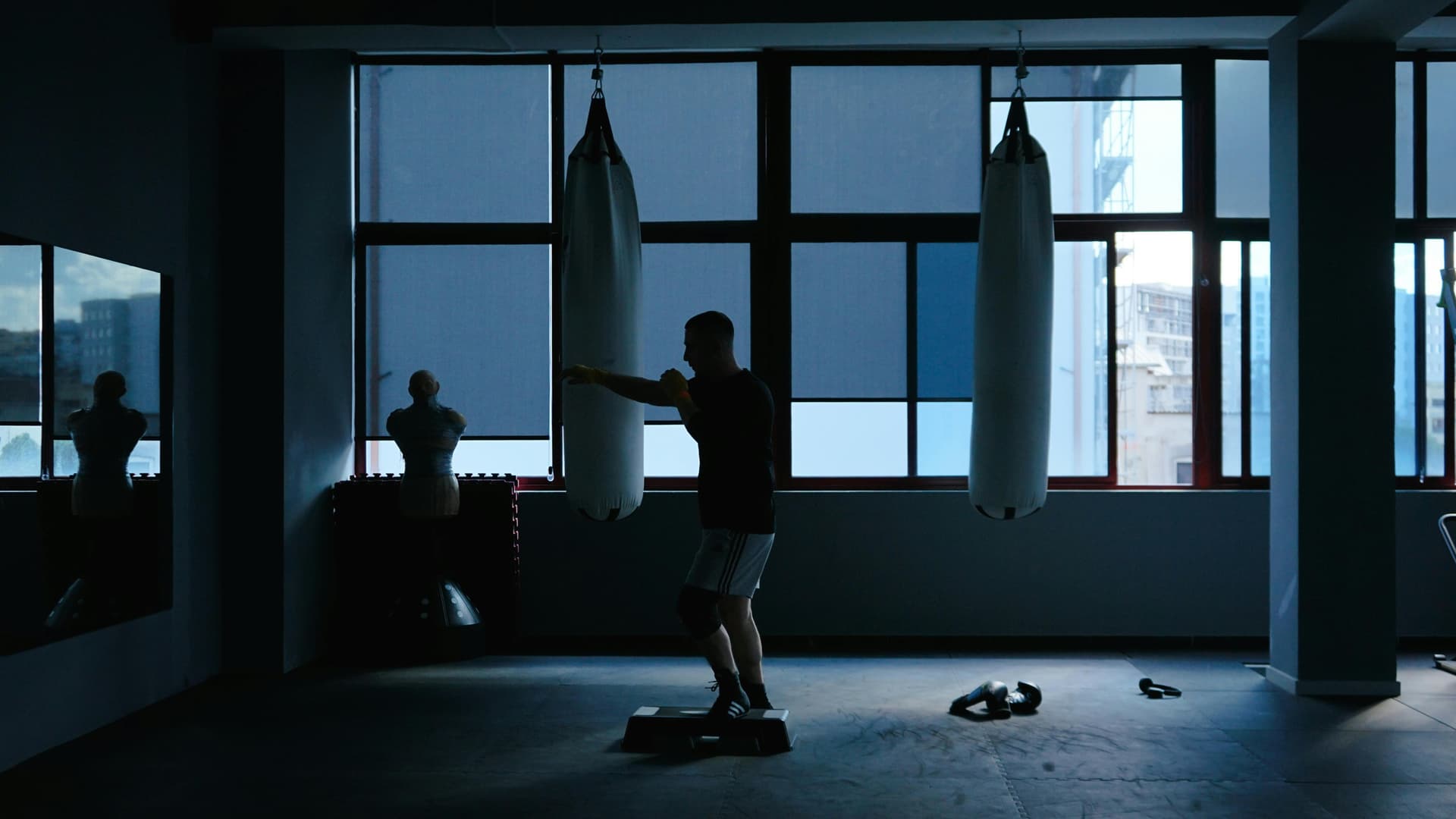 A boxer practices punching techniques in a dimly lit gym in Tirana, Albania.