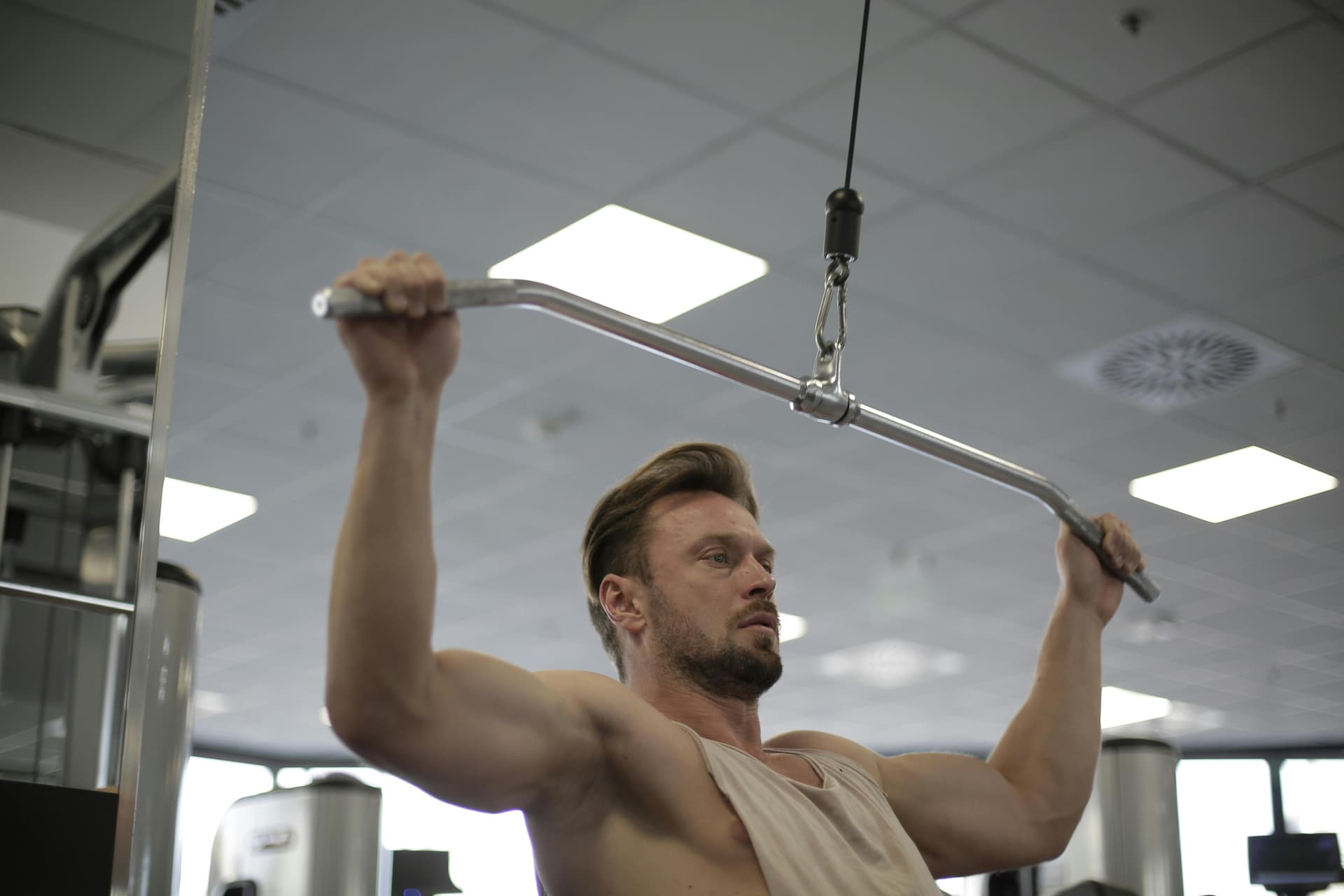 A focused man performing lat pulldowns in a modern gym environment.