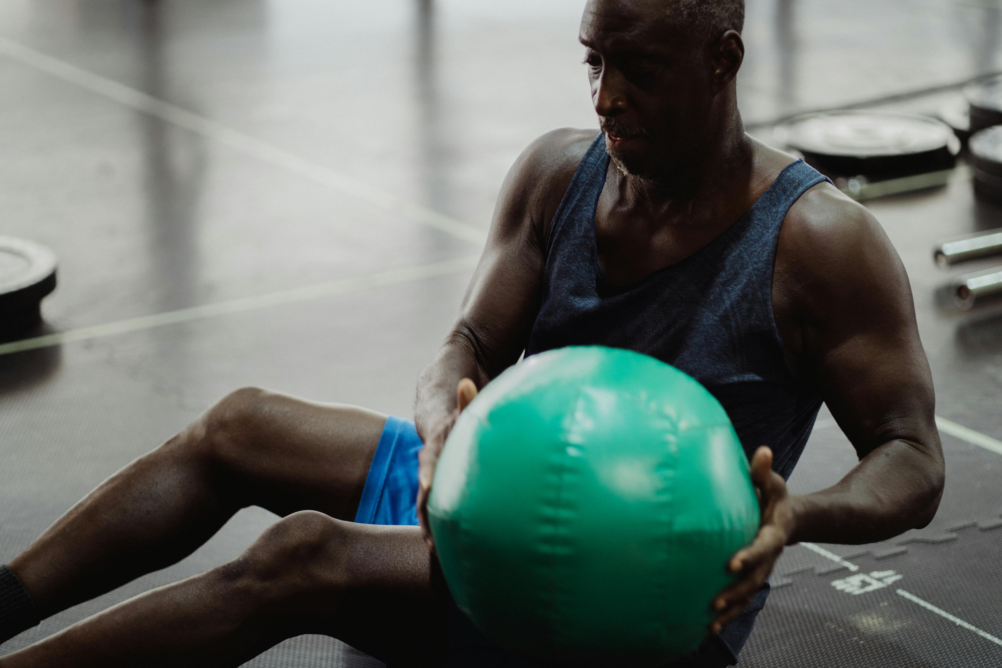 Adult male focused on workout with medicine ball in gym setting.