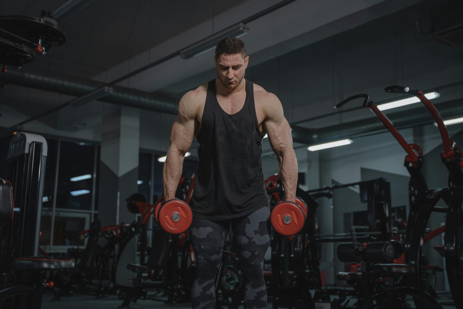 A strong man working out in a gym, lifting dumbbells with focus and intensity.