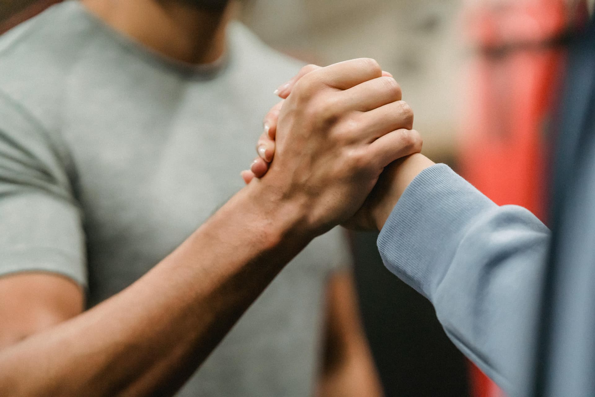 Close-up of a handshake between two individuals in a gym, symbolizing support and teamwork.