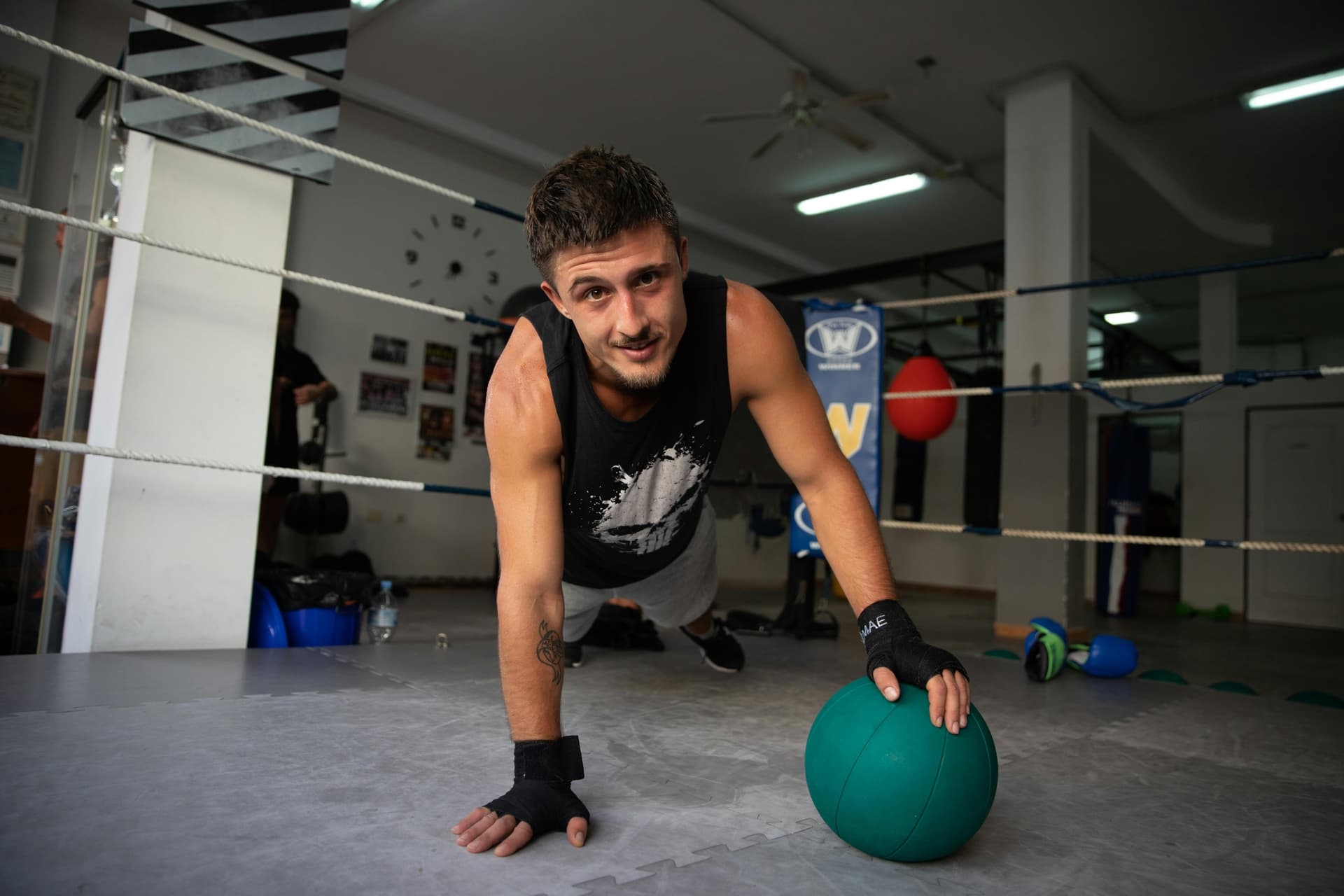 Fit young man doing push-ups in a gym using a medicine ball.