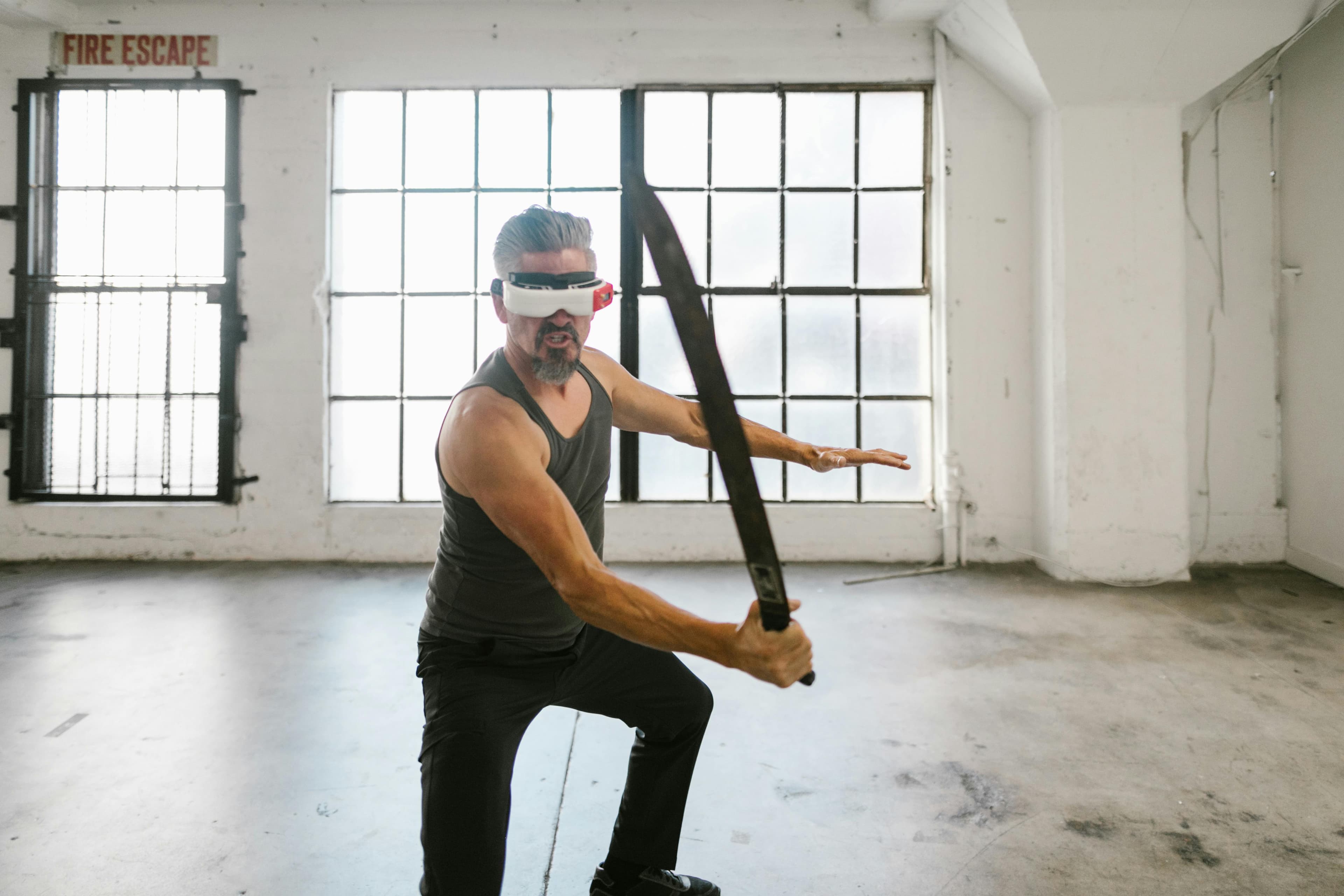 Man engaged in virtual reality sword training indoors, showcasing tech and fitness blend.