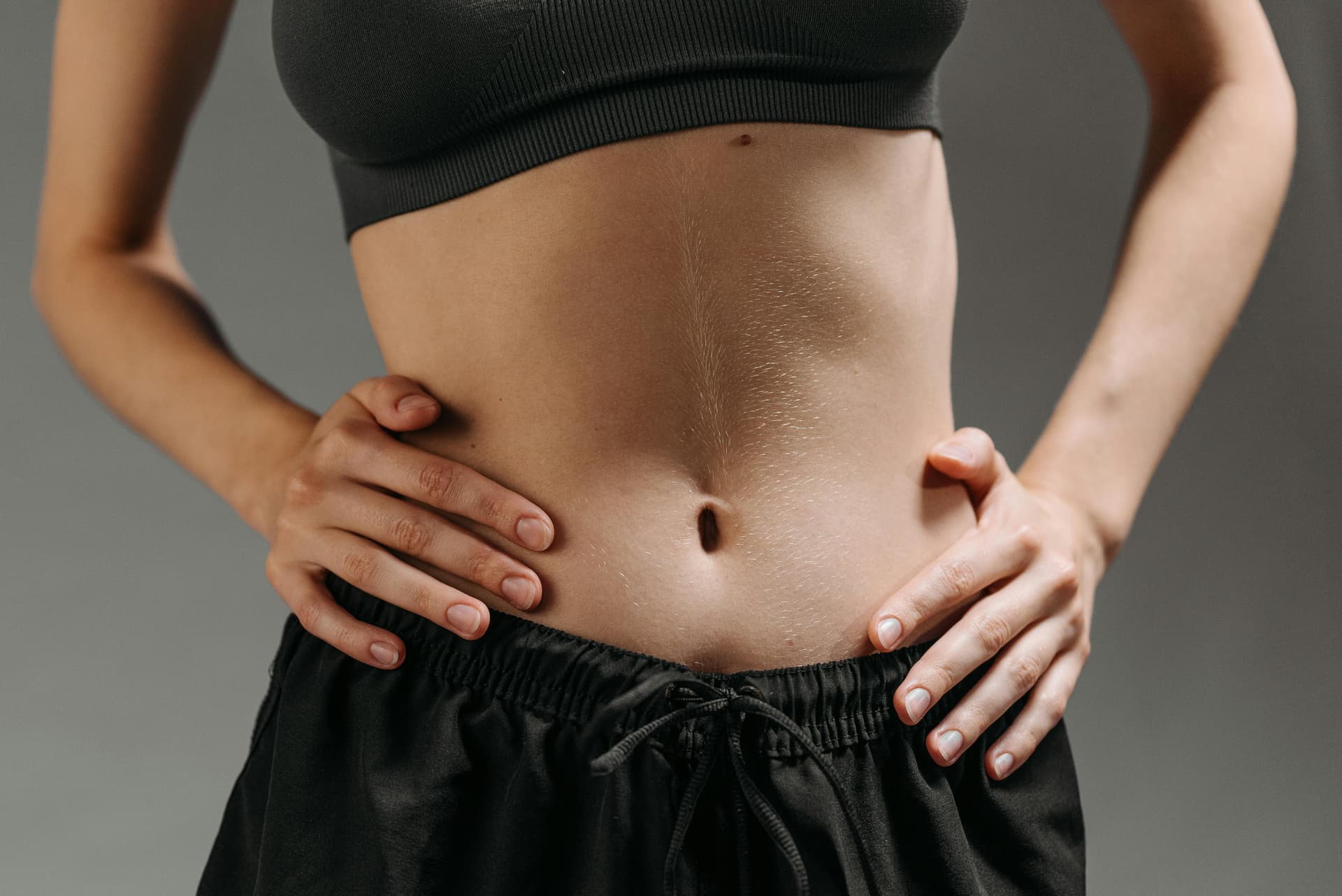 Focused shot of a woman's torso showing athletic physique in a studio setting.